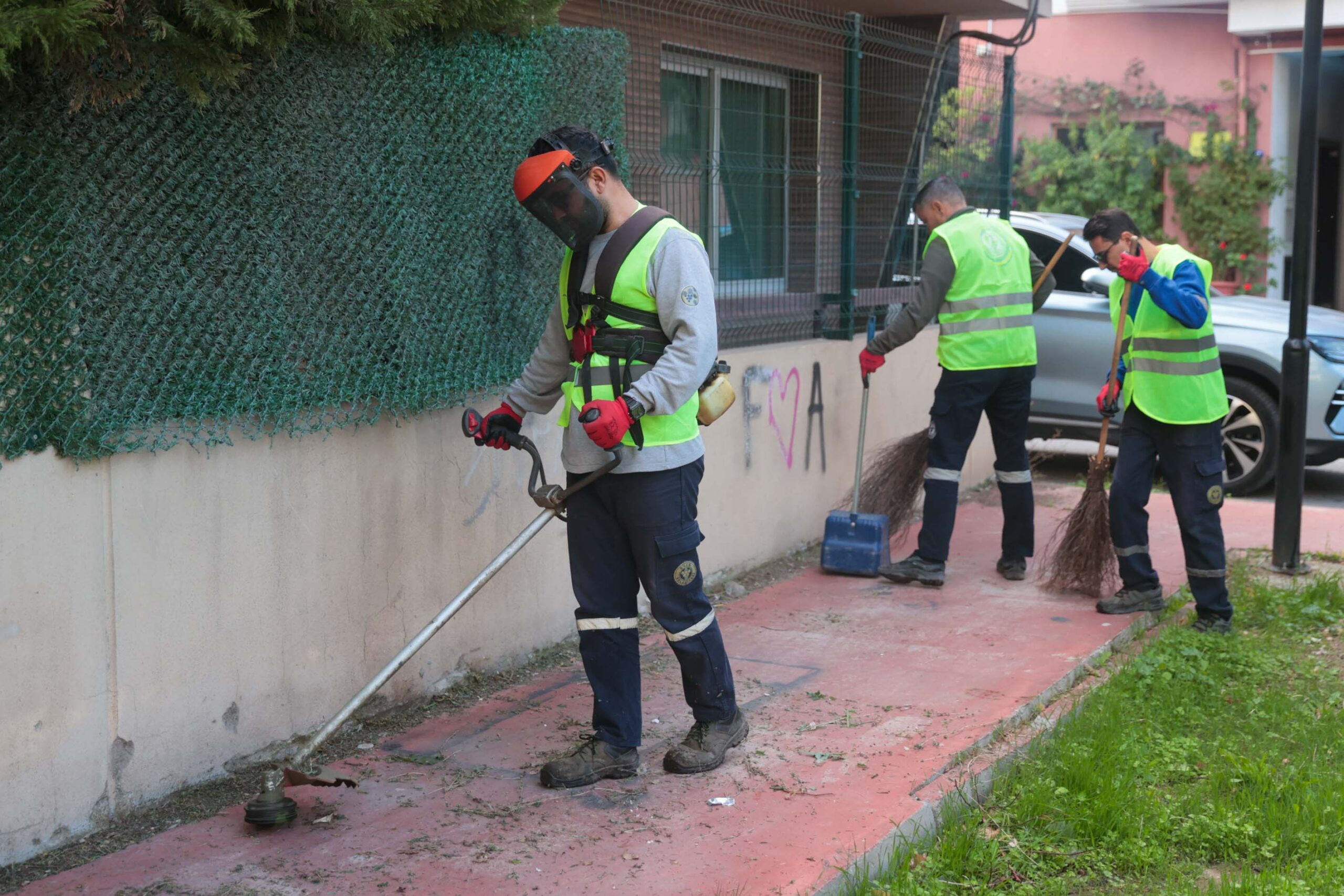 Buca Belediyesi temizlik ekipleri, bir parkta kosa ve budama çalışması yaparken